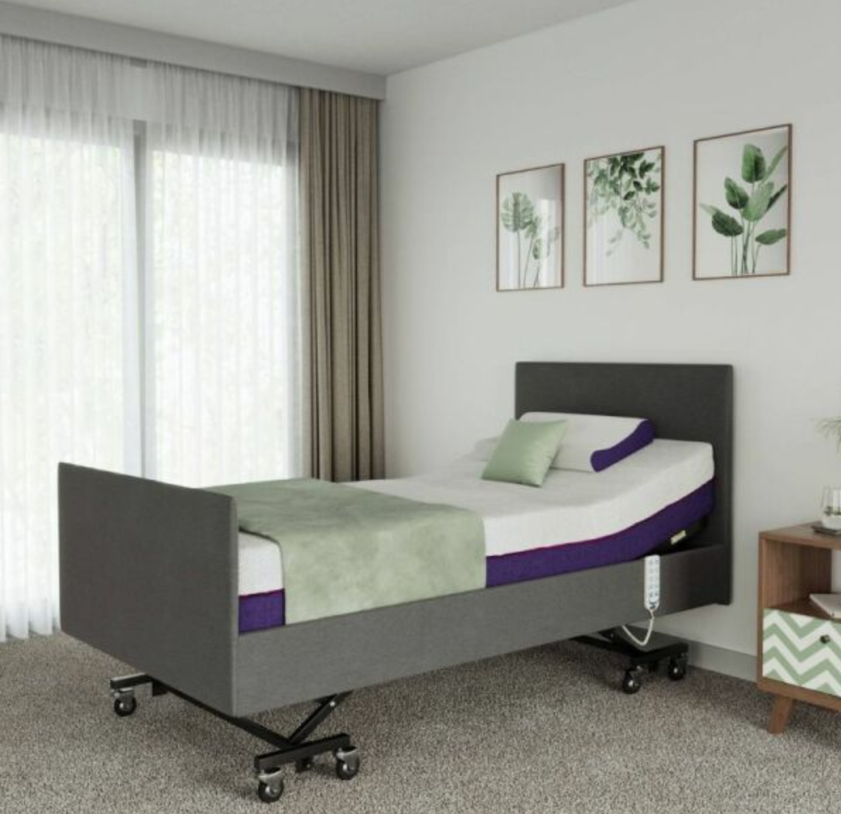 A gray motorized hospital-style bed frame with side rails and under-bed wheels, shown in a styled bedroom setting with white curtains, three framed botanical prints on the wall, and a small wooden side table.