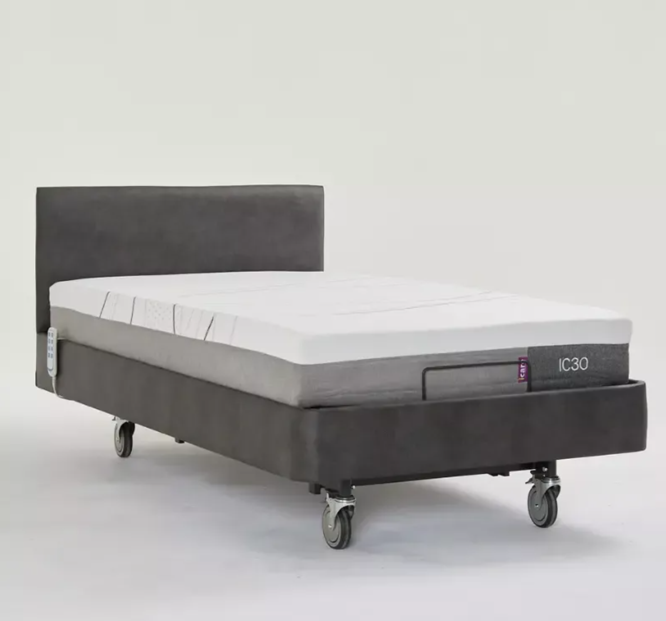 A dark gray upholstered bed frame with a white mattress, shown on castor wheels against a plain light gray studio background.