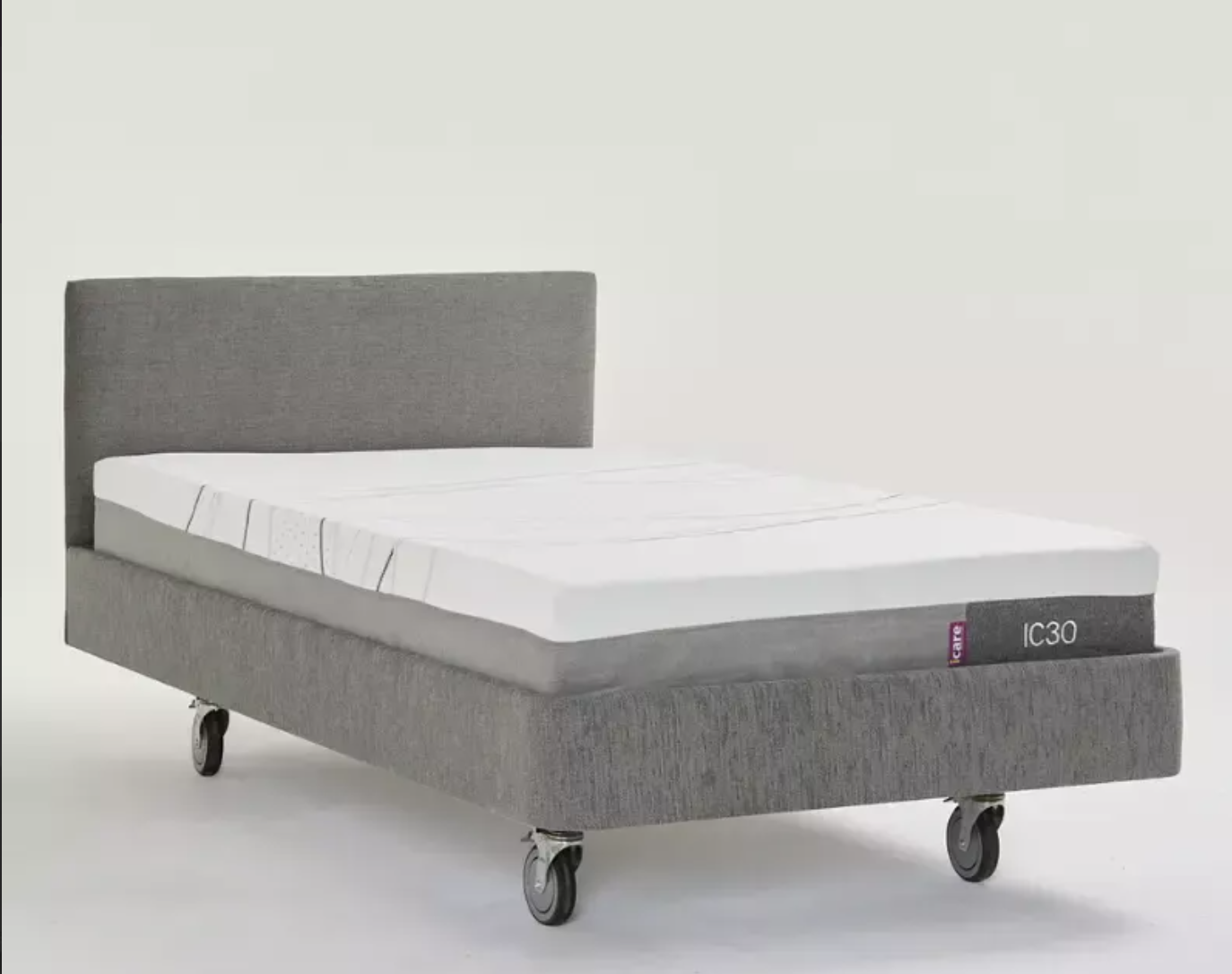 A gray upholstered bed frame with a white mattress, shown on a clean light gray studio background. The bed frame has a tall rectangular headboard and is mounted on casters, with a small side label reading 'IC30'.